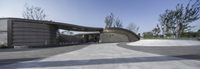 skate park with a concrete building and an arched ramp leading into the park with some trees