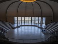 a big circular auditorium with stairs to the top of it and people walking around the bottom of the seating area