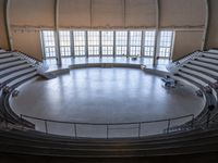 a big circular auditorium with stairs to the top of it and people walking around the bottom of the seating area