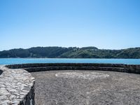 this circular bench on a rock bench overlooks the ocean and mountains around it on an island in the water