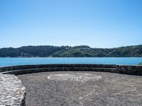 this circular bench on a rock bench overlooks the ocean and mountains around it on an island in the water