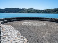 this circular bench on a rock bench overlooks the ocean and mountains around it on an island in the water