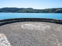 this circular bench on a rock bench overlooks the ocean and mountains around it on an island in the water