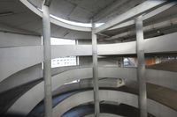 the bottom floor of a circular building with concrete columns and windows on it looking out over the street