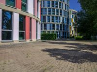 a circular building with colorful glass windows and doors in front of it and the reflection of its own