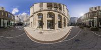 an image of a circular glass building on a street corner in the city center of town