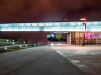 a view of a building and walkway lit up at night with light on it's surface