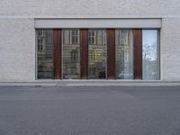 a person walking down the street next to a building with wood doors and windows on either side