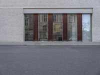 a person walking down the street next to a building with wood doors and windows on either side