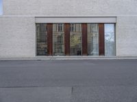 a person walking down the street next to a building with wood doors and windows on either side