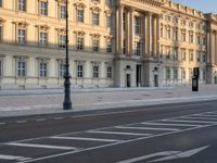 a big building with some white lines on the sidewalk in front of it and traffic lights