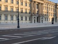 a big building with some white lines on the sidewalk in front of it and traffic lights