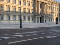 a big building with some white lines on the sidewalk in front of it and traffic lights