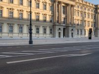 a big building with some white lines on the sidewalk in front of it and traffic lights