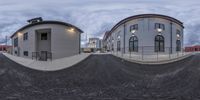 a 360 lens image of two buildings on a city street with a ramp, and another half empty street