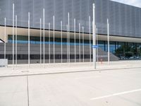 a large gray building with silver poles and glass windows next to it's entrance