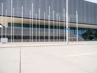 a large gray building with silver poles and glass windows next to it's entrance