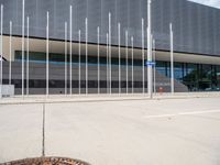 a large gray building with silver poles and glass windows next to it's entrance