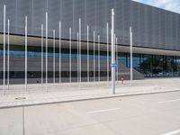 a large gray building with silver poles and glass windows next to it's entrance