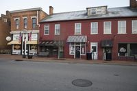 a large building sits along a street with shops and signs on it in front of a fire hydrant