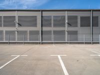 large steel metal building with sliding doors and two parking spaces with three people standing on the outside