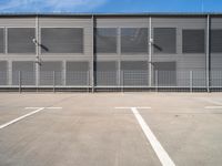 large steel metal building with sliding doors and two parking spaces with three people standing on the outside