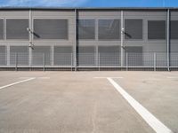 large steel metal building with sliding doors and two parking spaces with three people standing on the outside