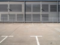 large steel metal building with sliding doors and two parking spaces with three people standing on the outside