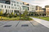 a city street surrounded by grass and tall buildings at the end of a street there is a paved pathway in front of the building