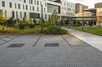 a city street surrounded by grass and tall buildings at the end of a street there is a paved pathway in front of the building