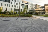 a city street surrounded by grass and tall buildings at the end of a street there is a paved pathway in front of the building