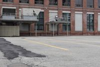 the empty parking lot has only snow on the ground in front of an old brick factory