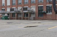 the empty parking lot has only snow on the ground in front of an old brick factory