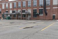 the empty parking lot has only snow on the ground in front of an old brick factory