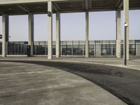 a parking lot with concrete pillars and glass railings on either side of the walkway