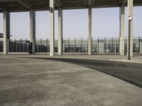 a parking lot with concrete pillars and glass railings on either side of the walkway