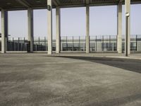 a parking lot with concrete pillars and glass railings on either side of the walkway