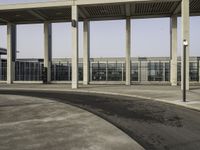 a parking lot with concrete pillars and glass railings on either side of the walkway