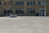 a bench sitting in front of a large brick building with many windows and an area with a sidewalk