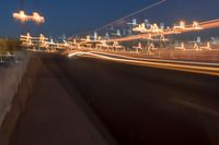 a city bridge at dusk has cars driving along it with buildings lit up in the distance