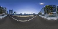 a panoramic view shows street traffic in front of the tall buildings on a bridge