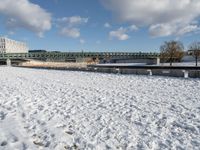 a white winter with a bridge and benches in front of it in the snow on the banks