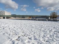 a white winter with a bridge and benches in front of it in the snow on the banks