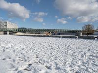 a white winter with a bridge and benches in front of it in the snow on the banks