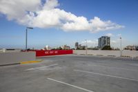 a empty parking lot in a big city with white and red cars parked nearby and buildings