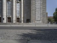 a man in green shirt skateboarding down a sidewalk next to some building facades and columns