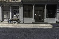 a man riding his motorcycle down a street past a restaurant with graffiti on it and people walking by