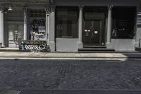 a man riding his motorcycle down a street past a restaurant with graffiti on it and people walking by