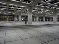 a room with rows of concrete columns on both sides and a brick floor and wall