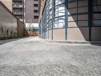 an empty sidewalk and brick building with glass front doors on it is next to a path